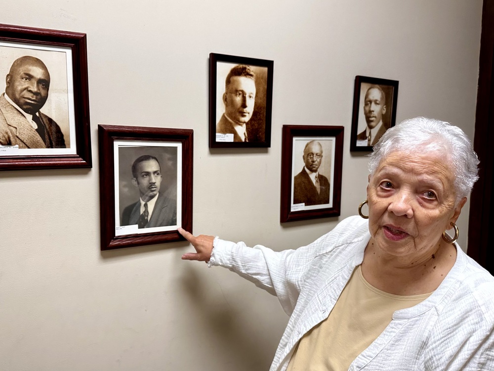 Longtime member Consuelo W. Harris with photos of early pastors of Carmel Presbyterian Church